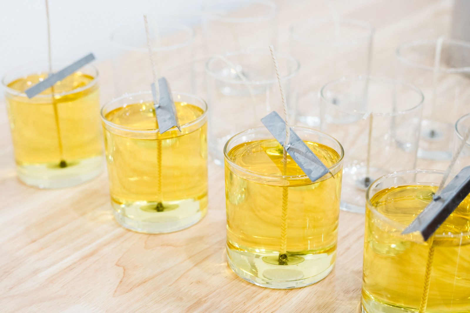 Freshly poured candles with wicks held in place by wick bars