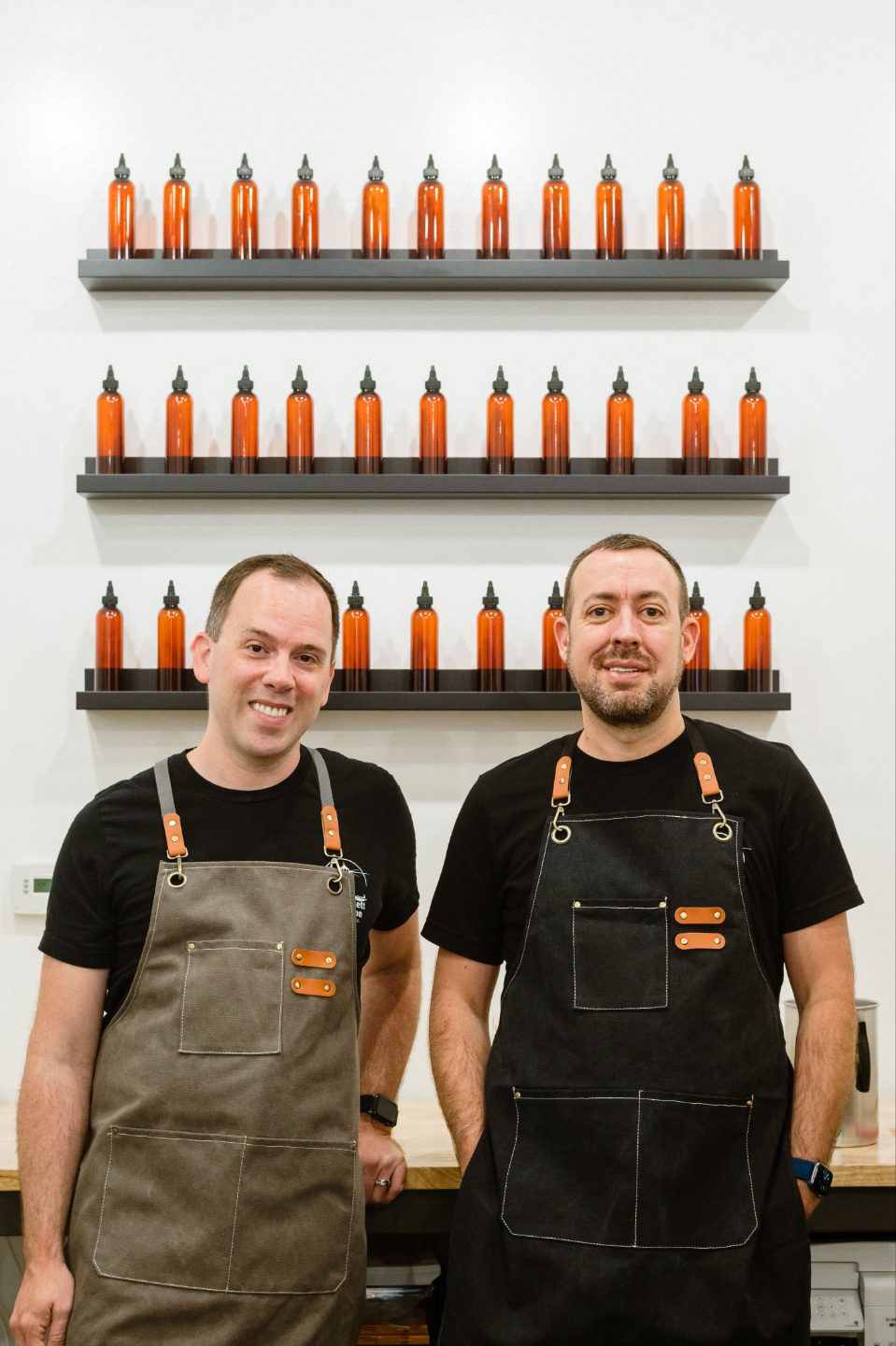 Chad and Sabastian Garsnett in their workshop in front of shelves of fragrance oils