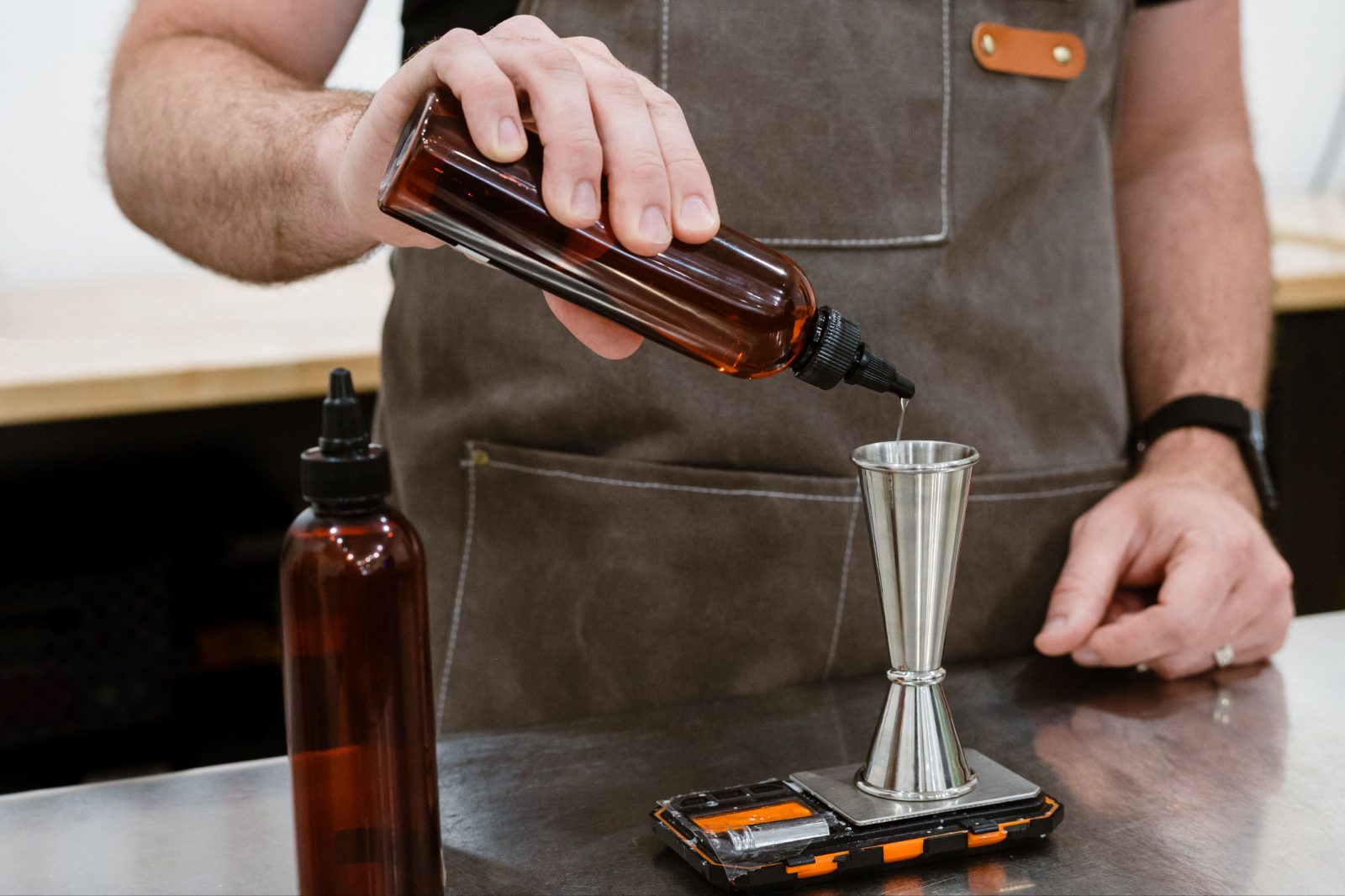 Pouring fragrance oil from an amber bottle onto a digital scale