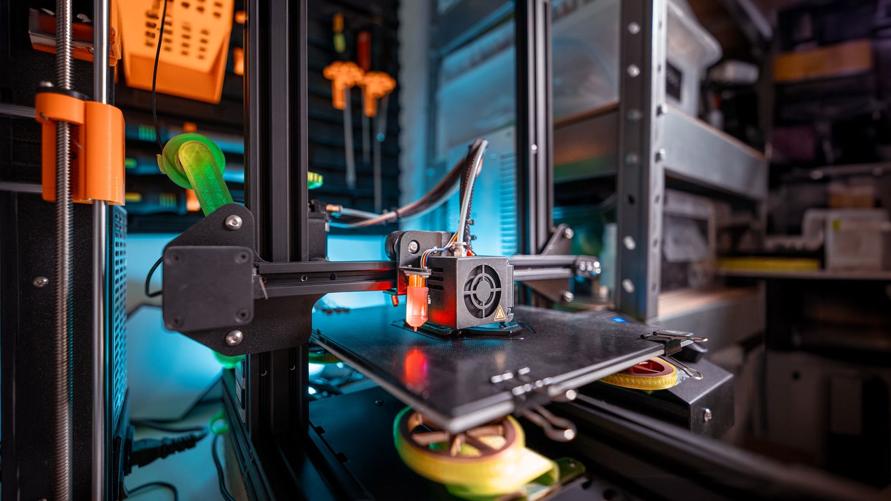 Impresora 3D FDM trabajando sobre una base de impresión en un taller.