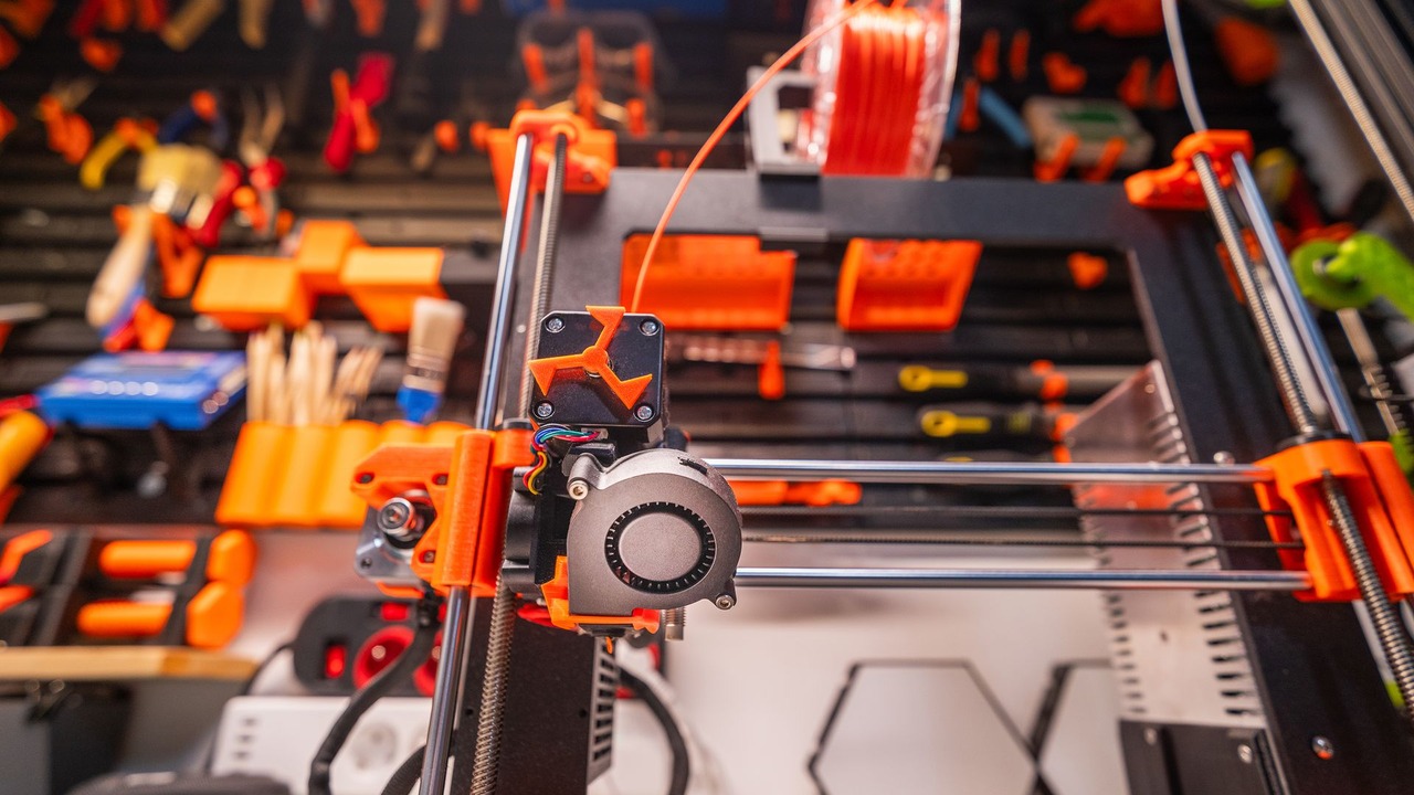 Impresora 3D FDM con filamento y herramientas en un taller.