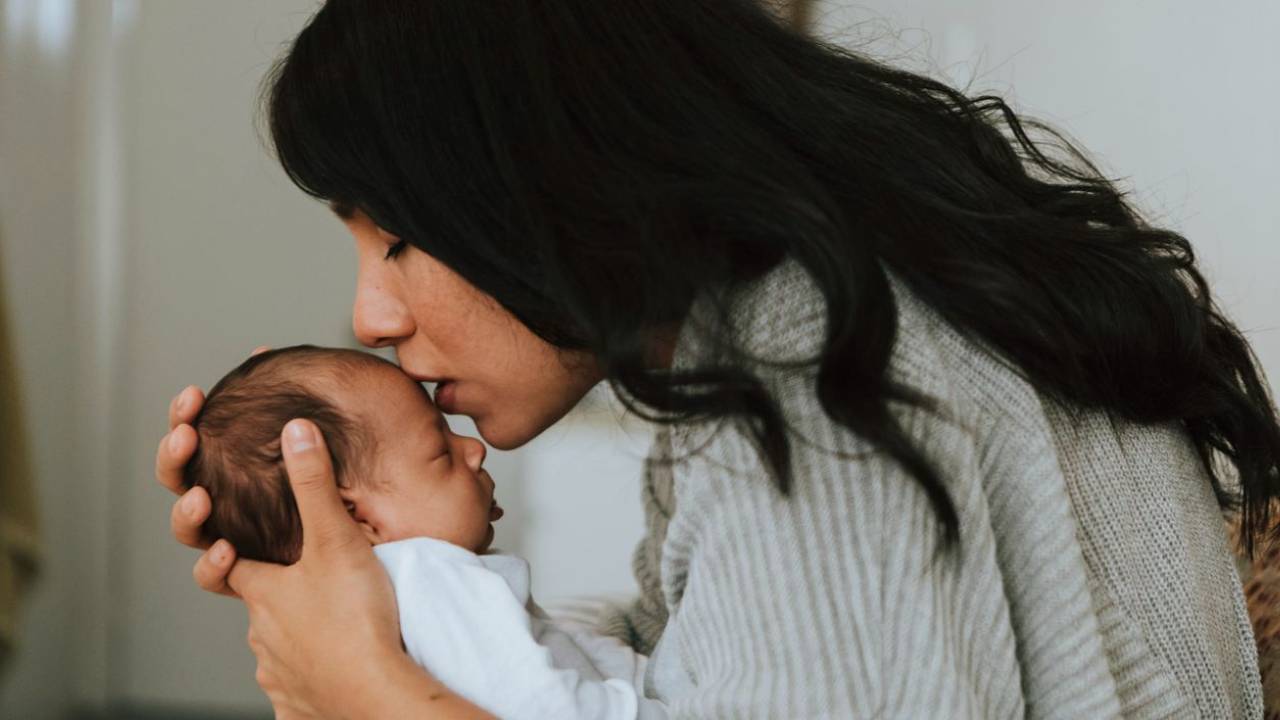mom kissing newborn baby's forehead