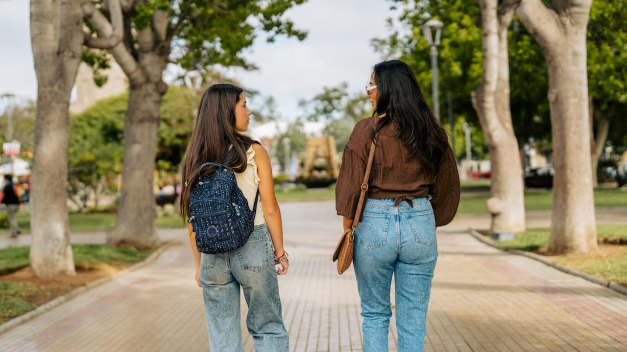 mom and teen daughter walking through park