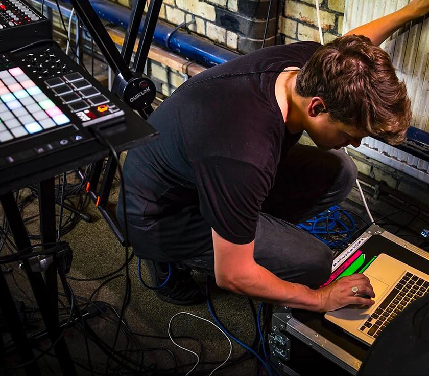 Craig Lowe at a laptop running Ableton Live side of stage