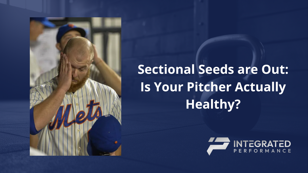 A high school pitcher touching his inner elbow with a concerned expression.