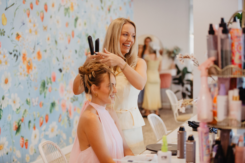 Charlie styling a laughing client in front of The Nest floral wallpaper