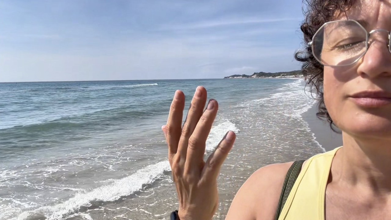 Le 3 regole d'oro per gambe leggere al mare Elena in riva al mare alza la mano per presentare le tre regole d'oro per gambe leggere d'estate