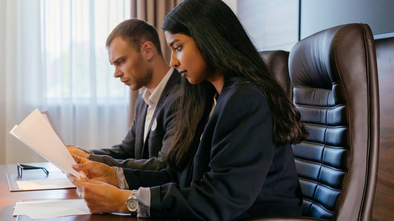 Two professionals reviewing audit documents at a desk