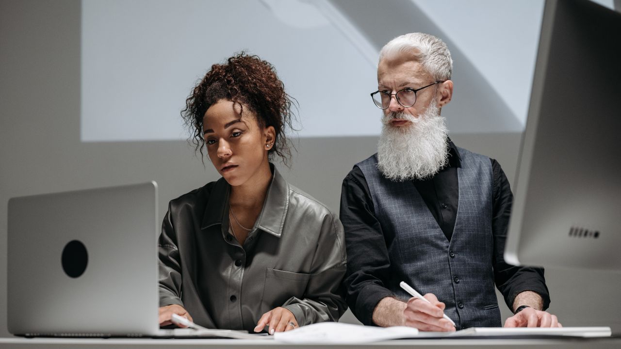 Two professionals reviewing information security work at a laptop