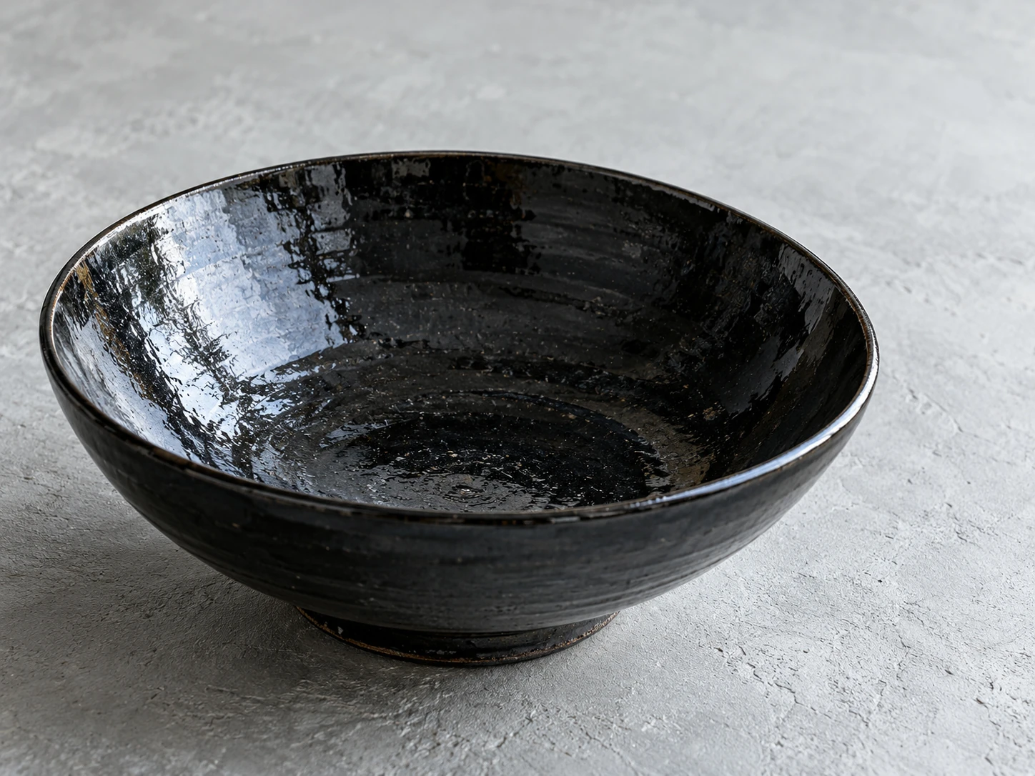 Dark glazed ceramic bowl showing a broad, controlled window reflection