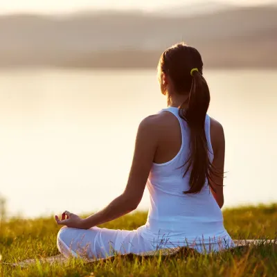 Woman meditating outdoors at sunrise for stress relief and mental clarity