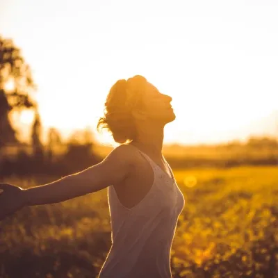 Woman breathing deeply outdoors at sunset practicing mindfulness
