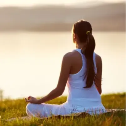 Woman meditating by a lake outdoors practicing yoga and mindfulness