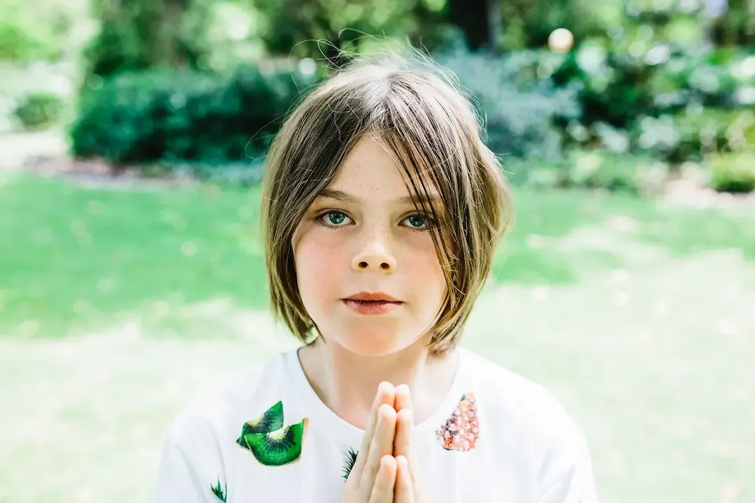 Child with hands in prayer position practising mindfulness during a kids yoga session