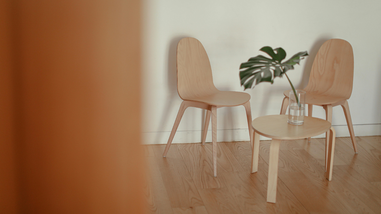 Minimalist room with two wooden chairs and a three-legged wooden table symbolizing balance and marriage growth