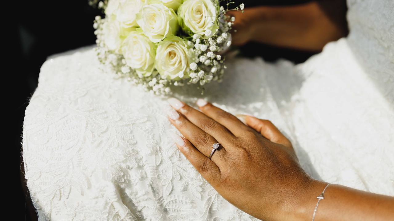 Faceless bride holding a bouquet of white roses with her wedding ring visible