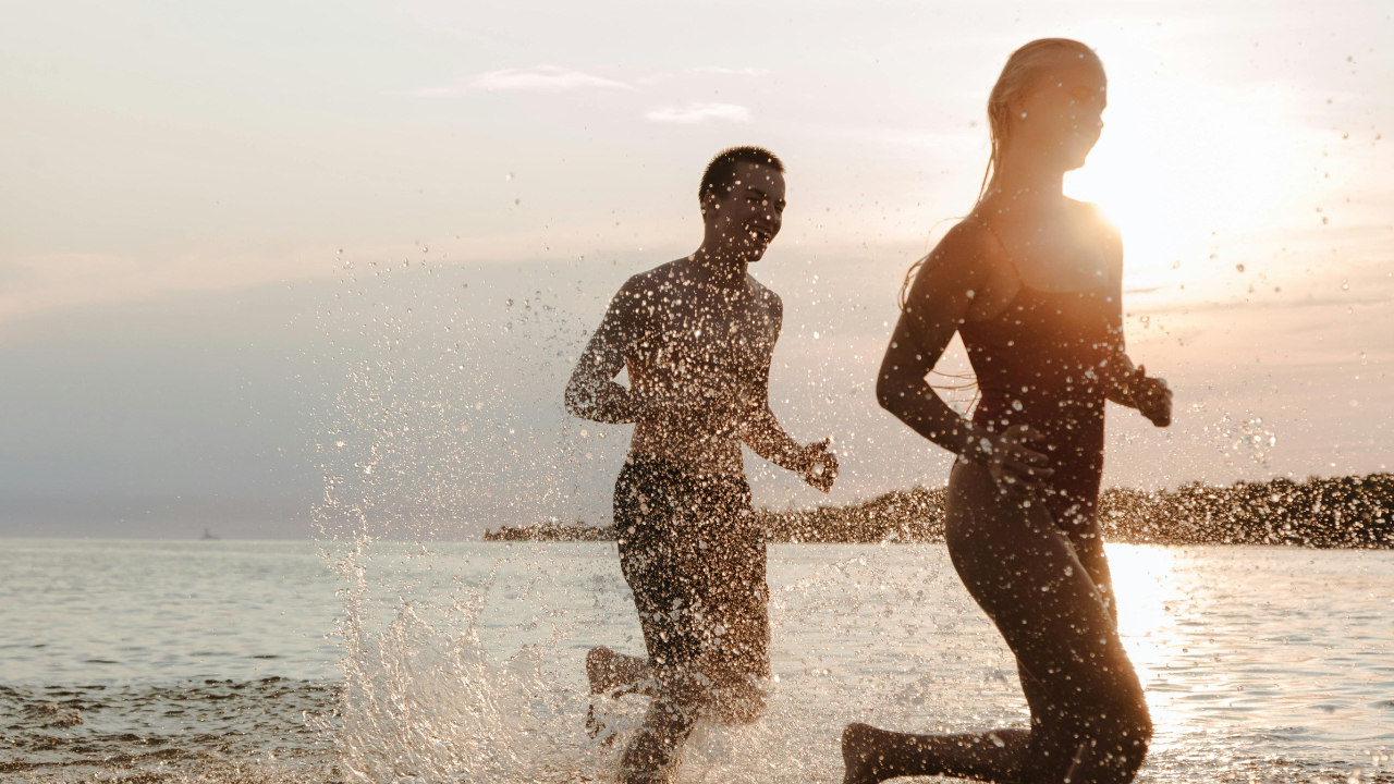 Husband playfully chasing his wife through the ocean on a beach, symbolizing emotional connection, romance, and pursuing your spouse in marriage.