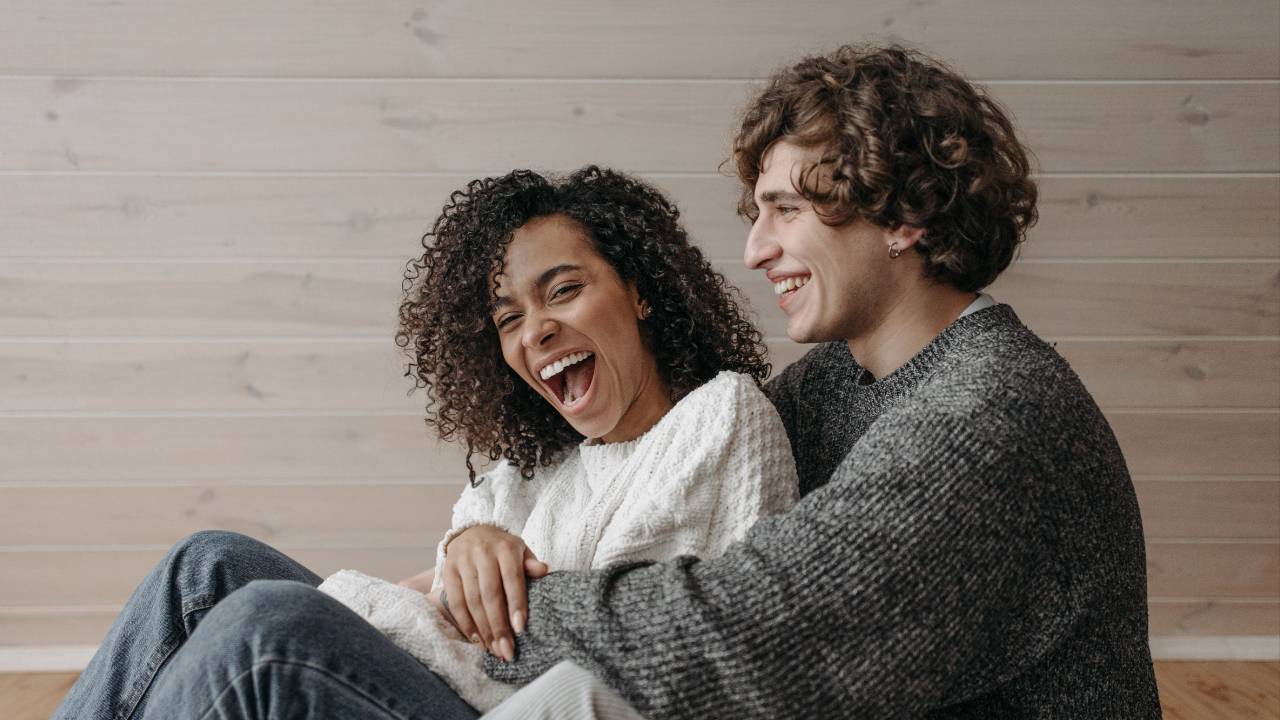 Candid couple laughing together as the man hugs the woman from behind