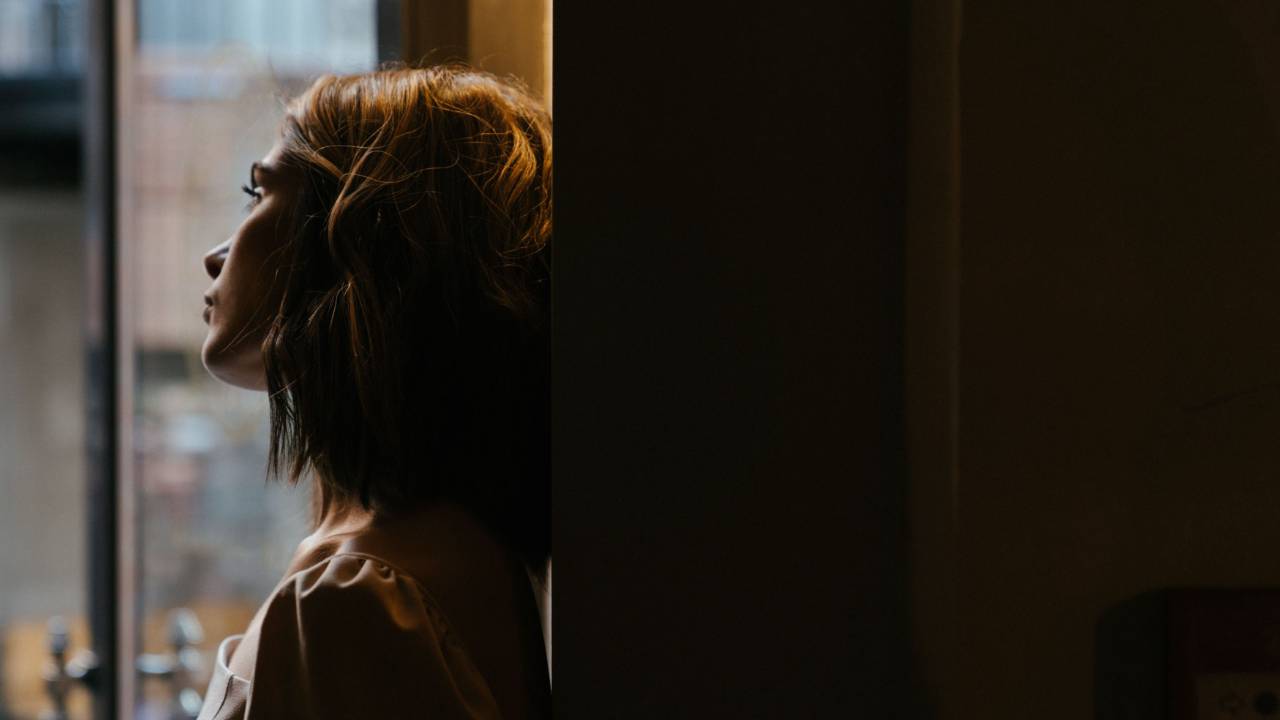 Thoughtful woman leaning against a wall, reflecting on her marriage.