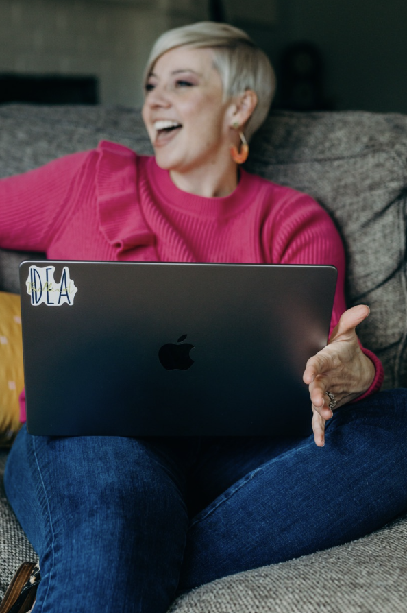 Casey Watts laughing on the couch with her laptop
