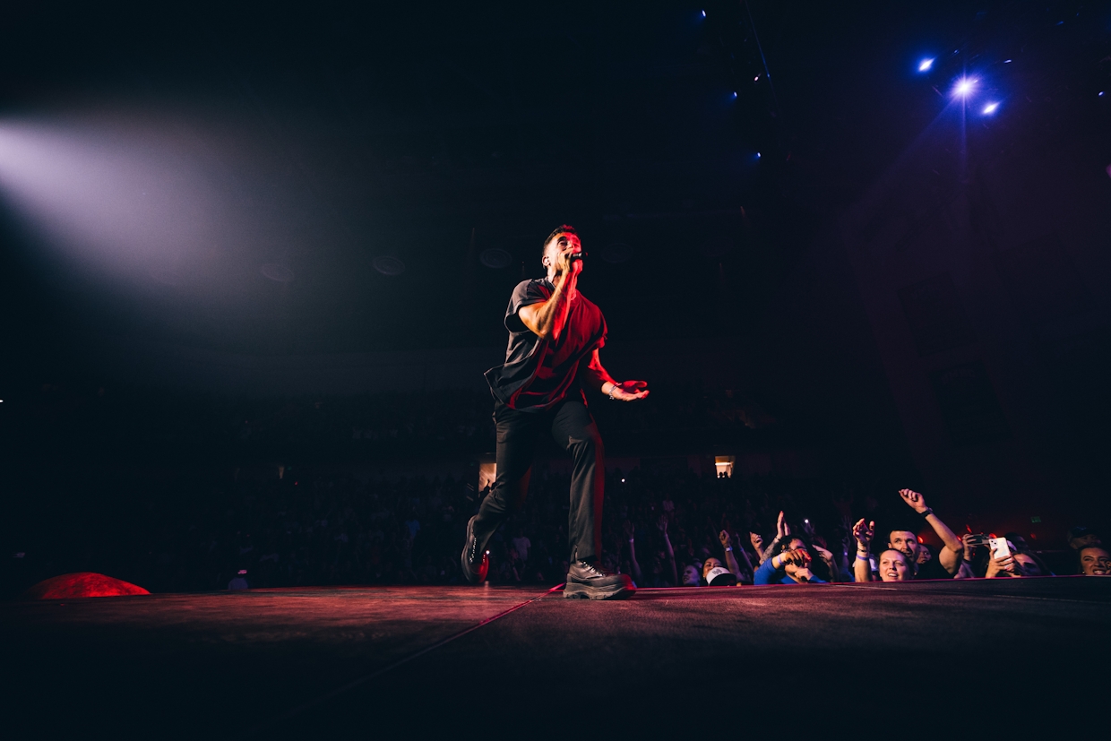 Worship concert moment with artist on stage and crowd reaching forward during a powerful night of surrender Phil Whickham