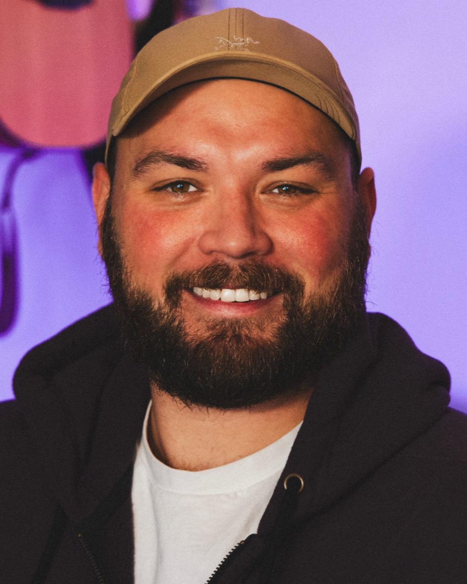 Justin Volz, smiling, in a cap and dark hoodie
