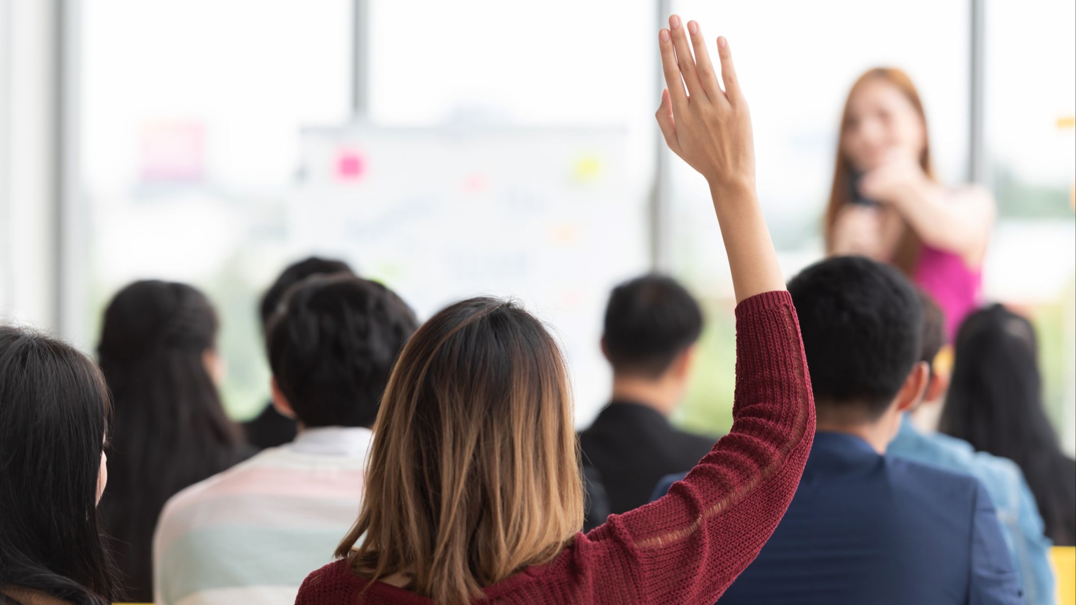 Woman raising her hand in a group of people.