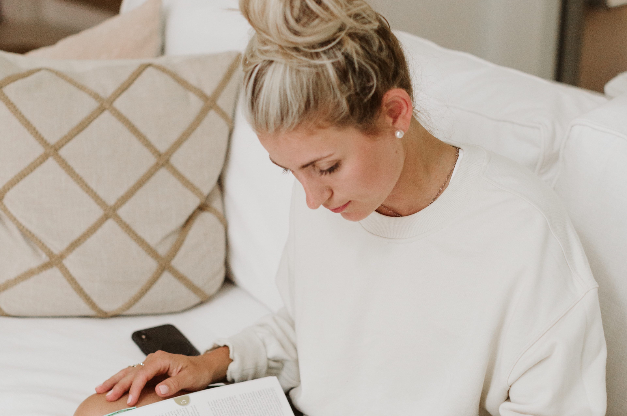 Woman reading a book while sitting on a couch.