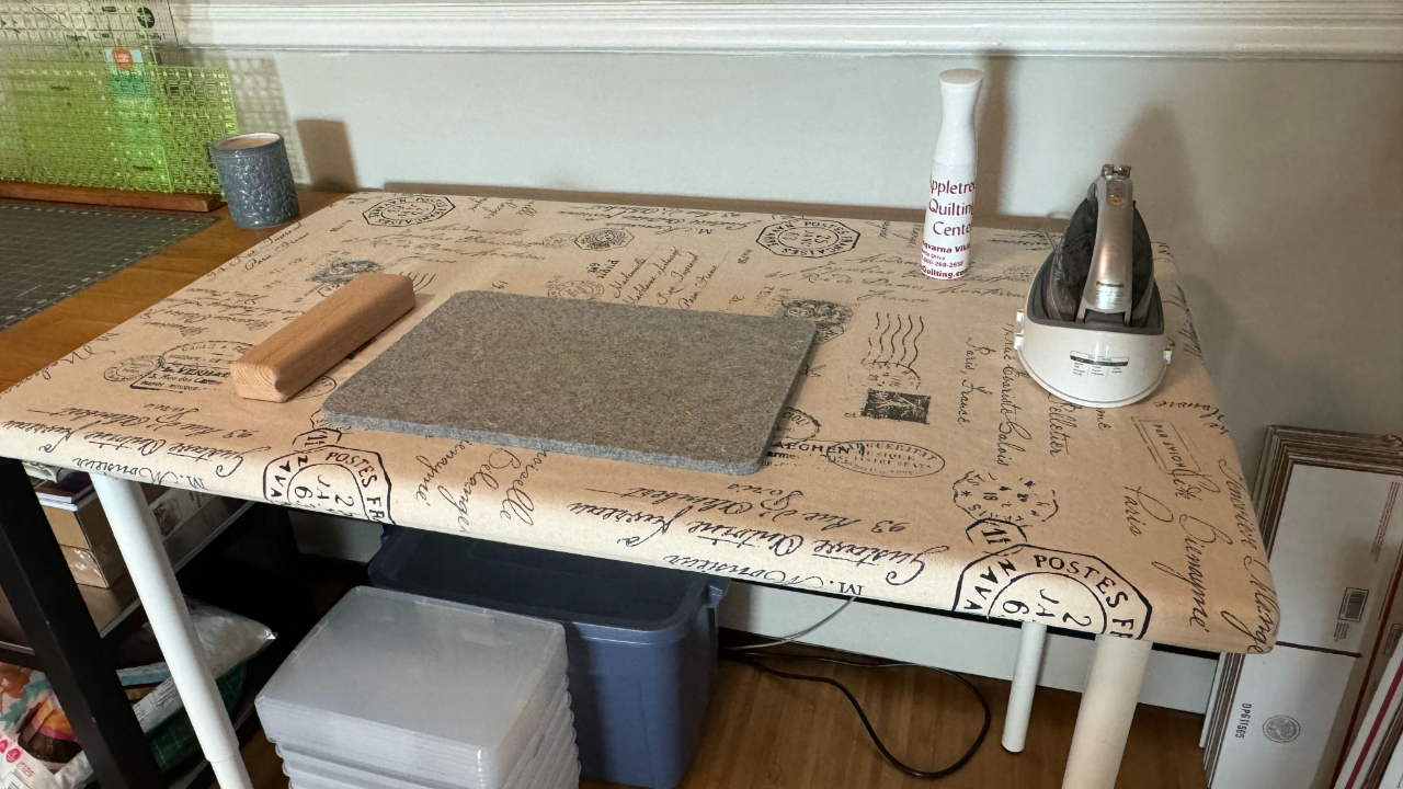 a pressing table with an iron, pressing mat, and tailor's clapper