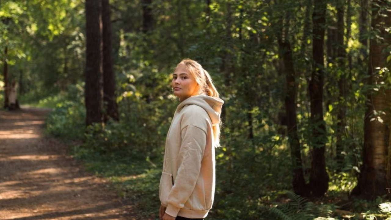 Young adult woman standing confidently in nature, reflecting on personal growth, self-discovery, confidence, and finding purpose in life