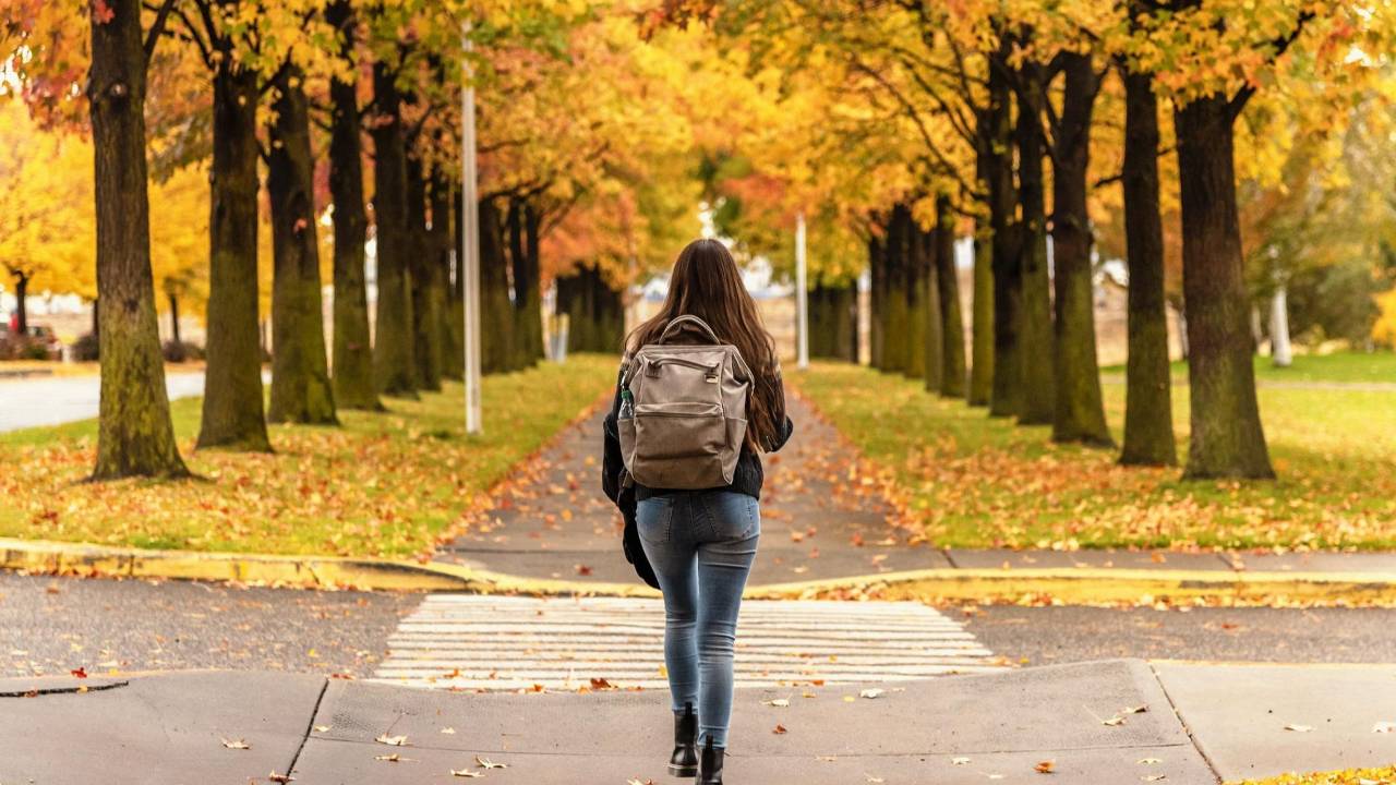 Young adult woman walking confidently toward college at the start of the fall semester