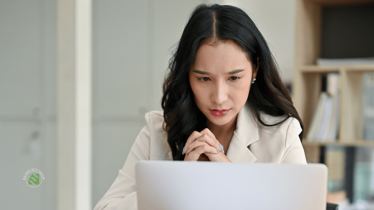 A professional sitting with a laptop open, paused mid-task, looking thoughtful 
