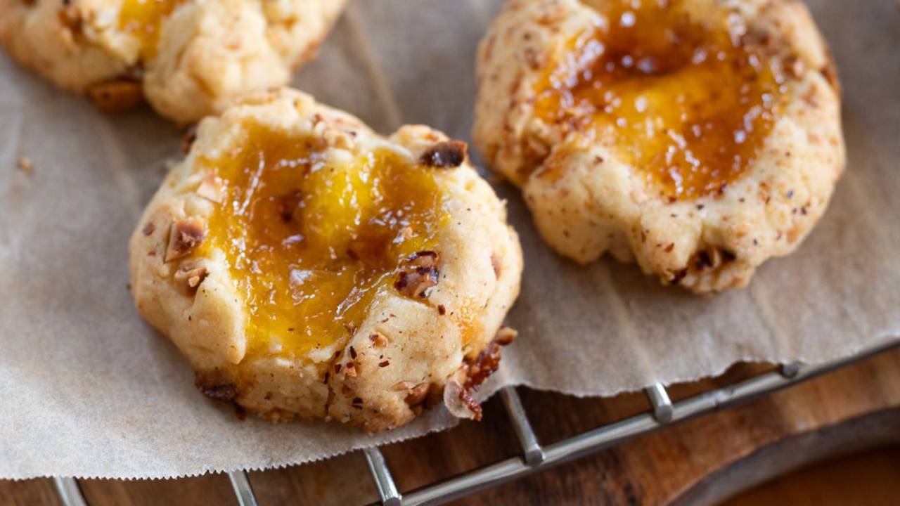 Hazelnut crusted jam drop cookies filled with jams in a heart shape, cooling on a wire rack