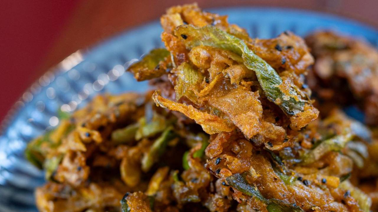 Crispy golden veggie peel bhajis made from vegetable scraps, piled on a plate