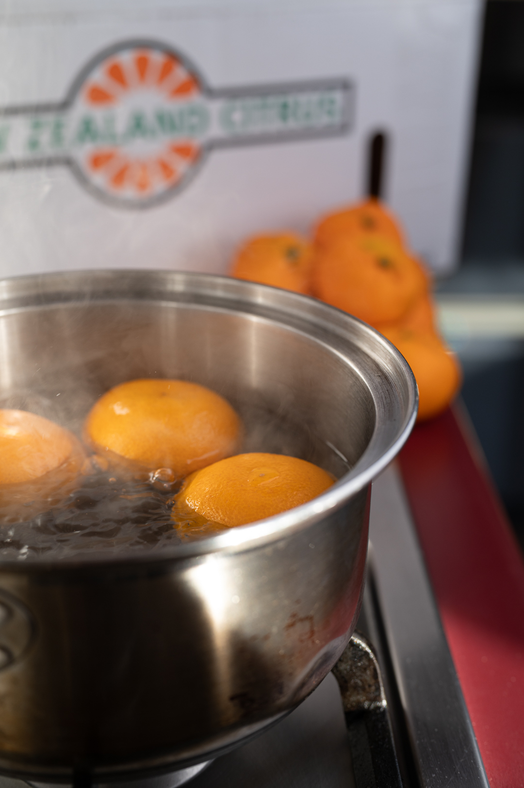 Whole satsumas simmering in a saucepan of water
