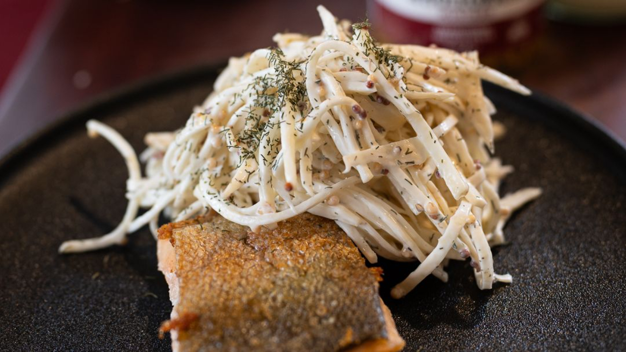 Classic French celeriac remoulade on a plate with seared fish,  fine julienned celeriac in a creamy wholegrain mustard and lemon dressing, garnished with dill