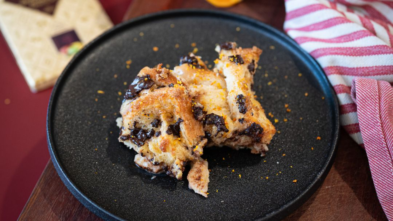 Baileys bread and butter pudding with dark chocolate and orange on a plate, golden and crunchy on top with a custardy centre.