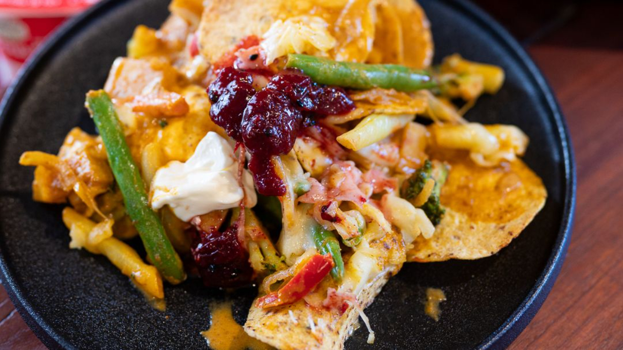 Vegetable curry nachos topped with melted cheese and sour cream and plum kasundi, on a plate