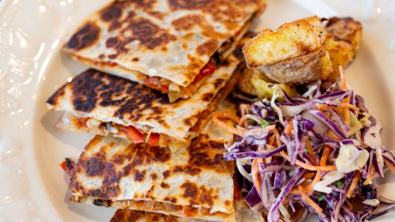 Mushroom quesadilla cut into wedges with melted cheese, served with crispy air fryer potatoes and slaw