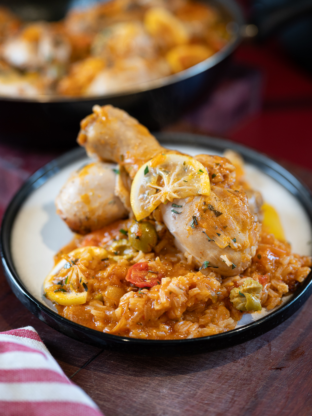 One pan peri peri chicken and rice with olives and lemon in a bowl, juicy chicken legs on top of saucy jasmine rice