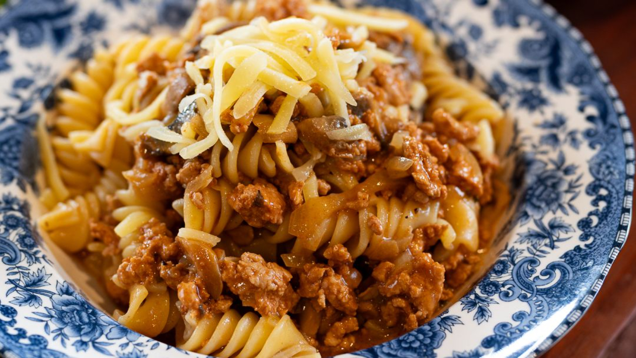 Creamy pork ragu pasta served in a bowl topped with grated cheese