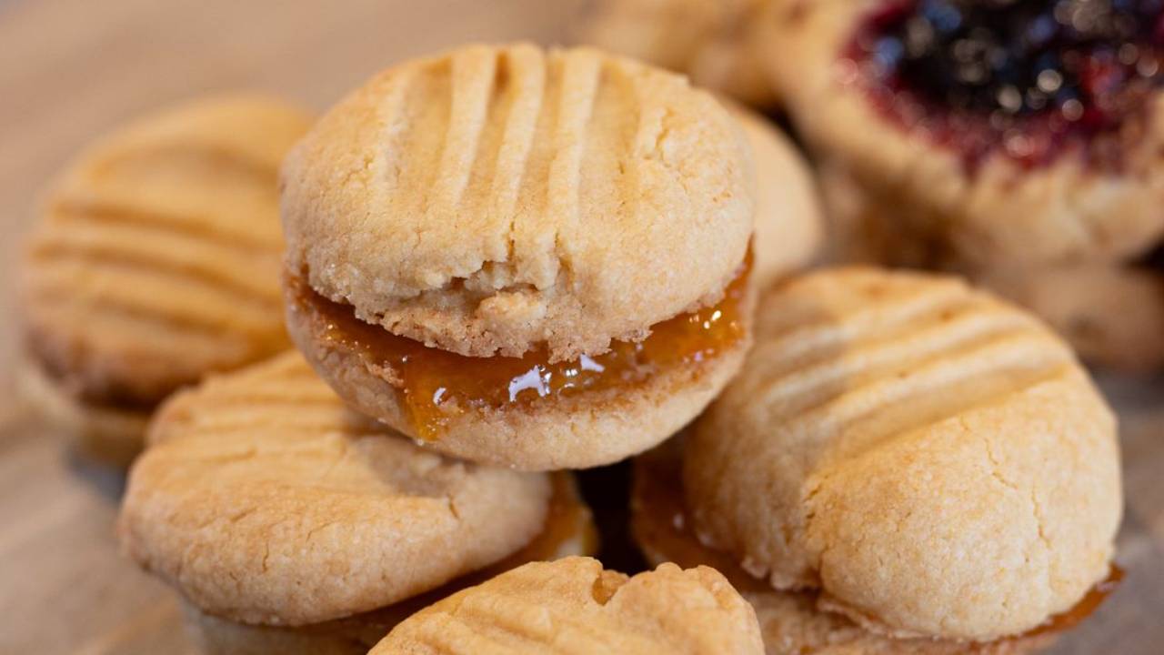 Homemade custard powder yoyo biscuits with fork-pressed tops, on baking paper on a wooden board