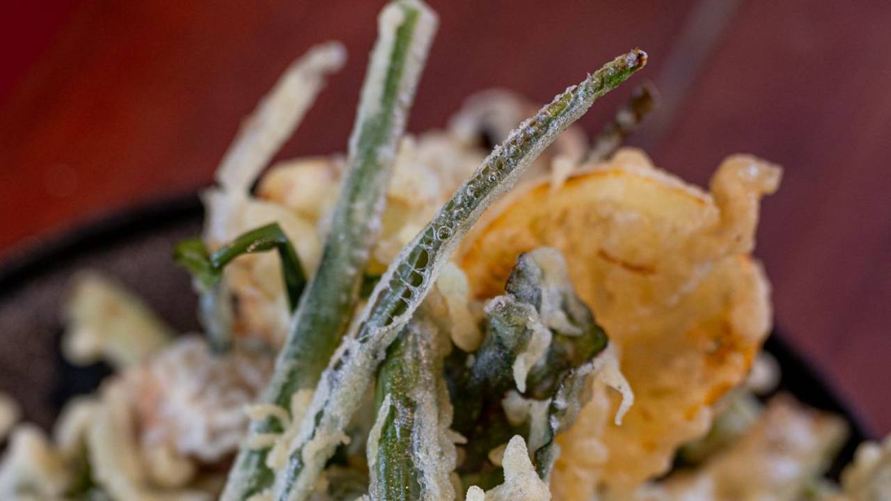 Crispy battered vegetable fritto misto with lemon slices and beetroot leaves, served with curried aquafaba mayo