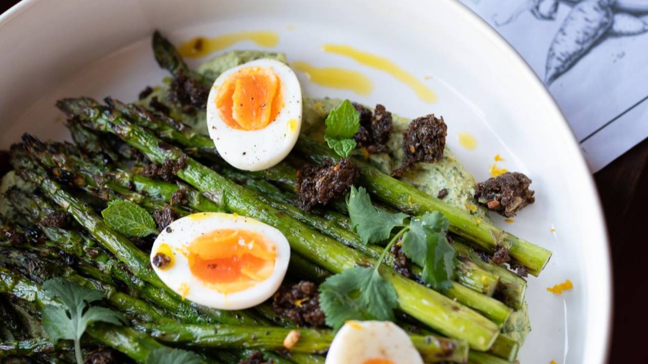 Grilled asparagus salad on green goddess hummus with jammy halved eggs and lemon breadcrumbs on a platter