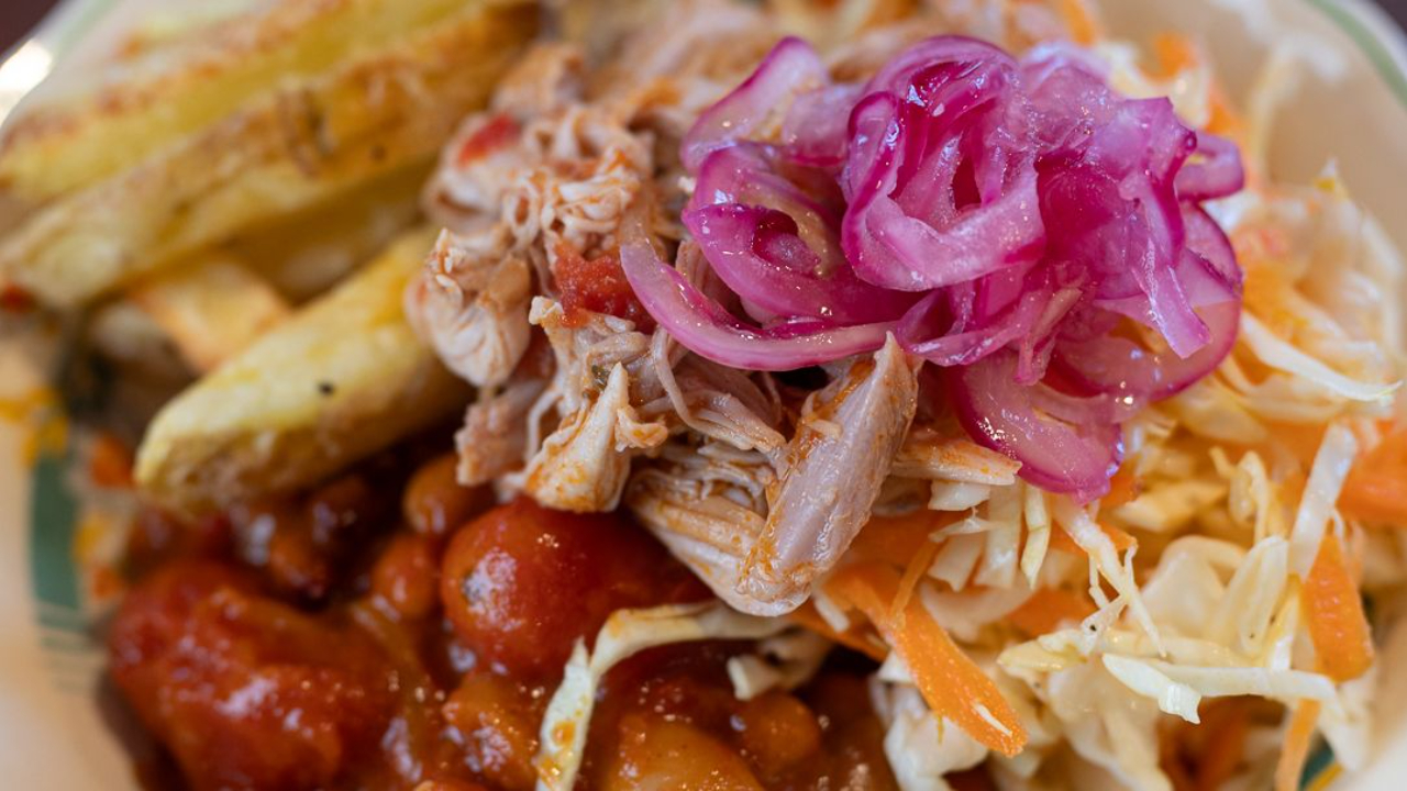 Mexican pulled chicken with spiced bean chilli, crispy chips and lemony cabbage slaw served on a plate