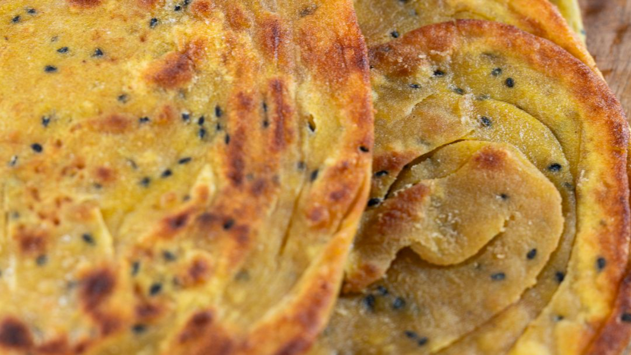 Flakey golden butter parathas stacked, showing the layered crispy texture