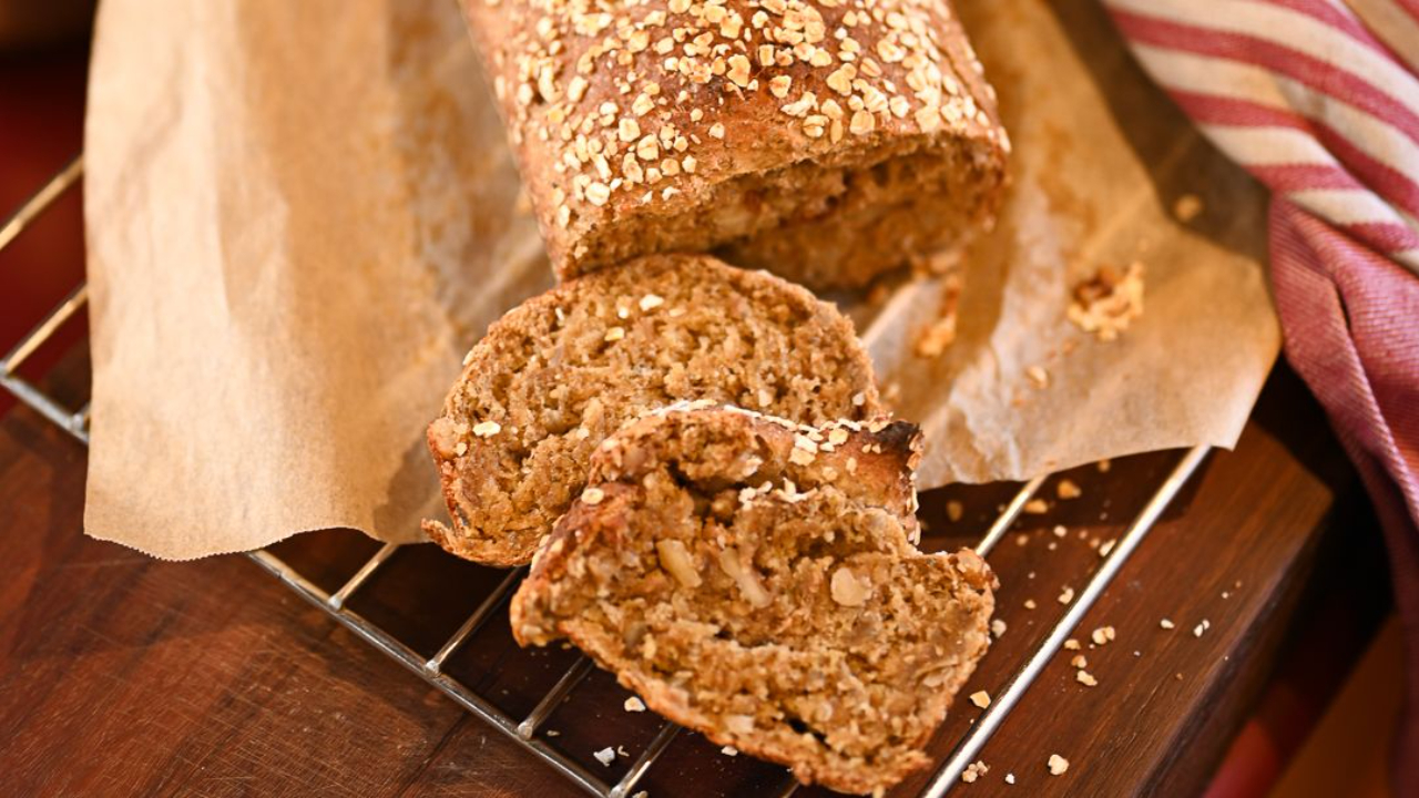 Sliced seeded porridge loaf on a wire rack showing a moist dark crumb with sunflower seeds walnuts and chia throughout