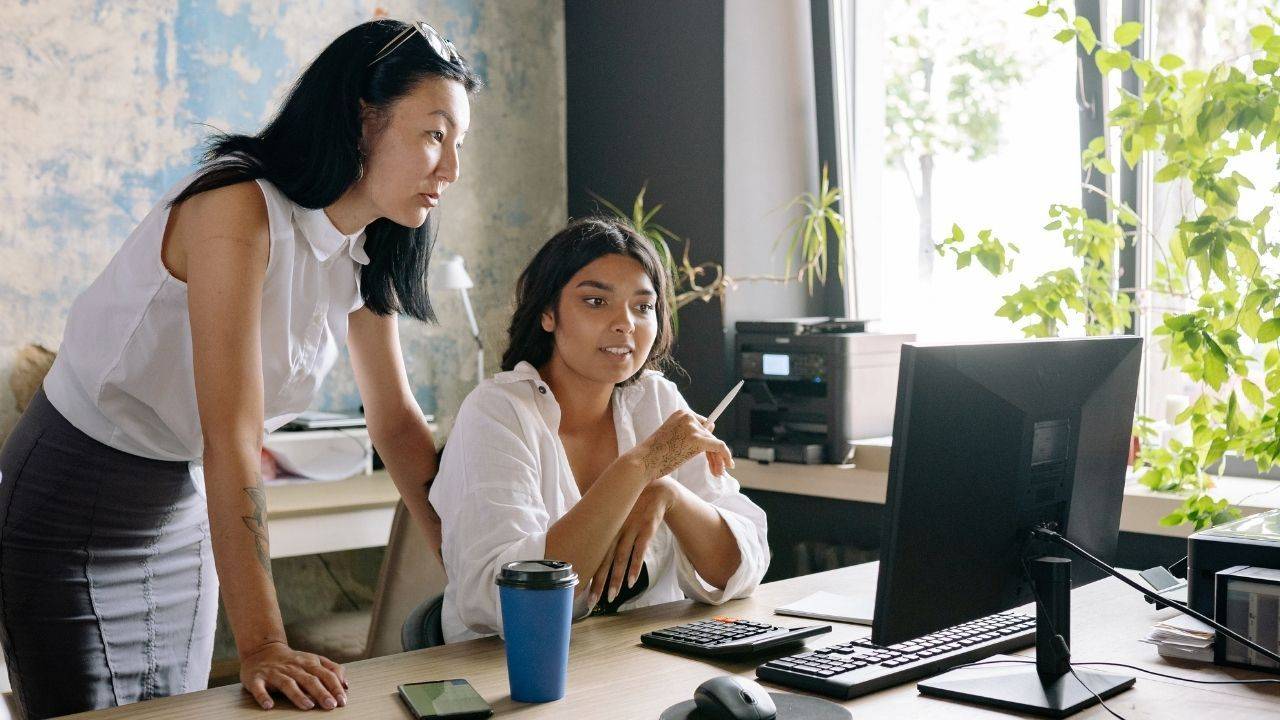 an asian and an indian woman are looking at a computern are looking at a 