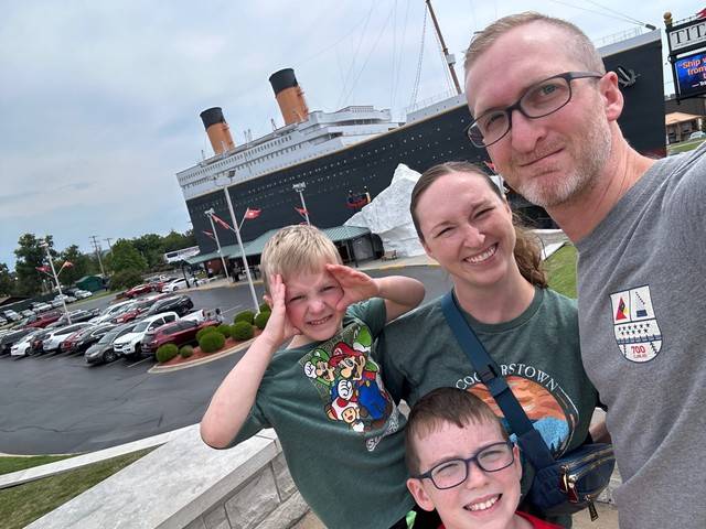 A family posing in front of a large passenger ship