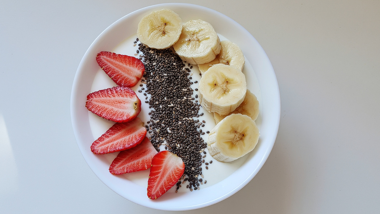 Bowl of Greek yogurt topped with sliced strawberries, bananas, and chia seeds